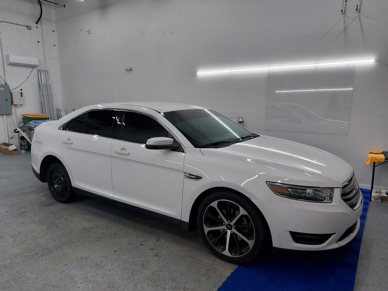 A white ford taurus is parked in a garage.