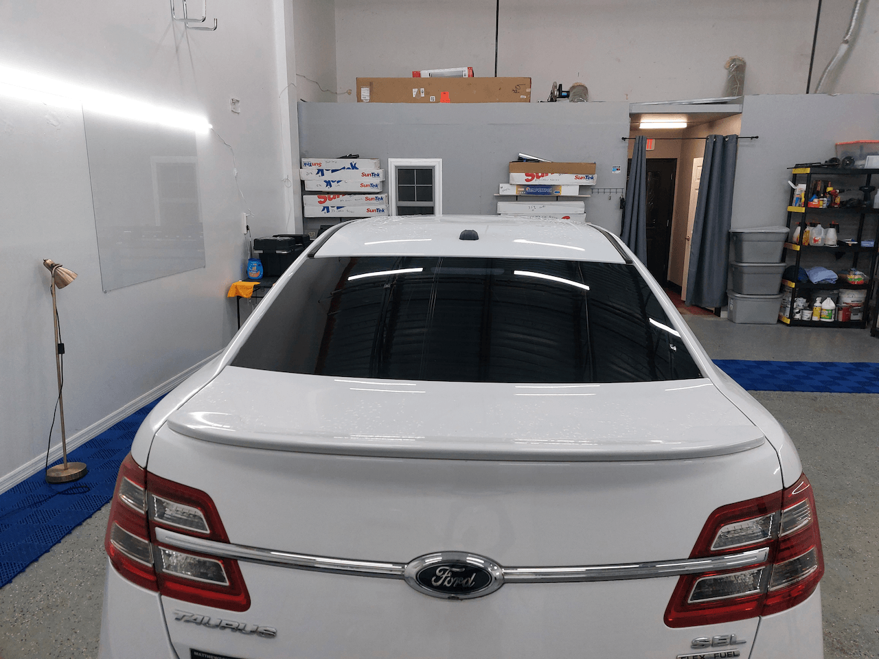A white car is parked in a garage with the trunk open