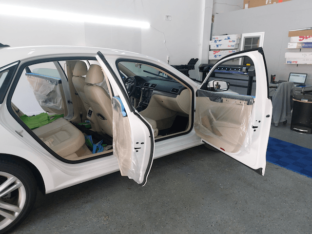 A white car with its doors open in a garage