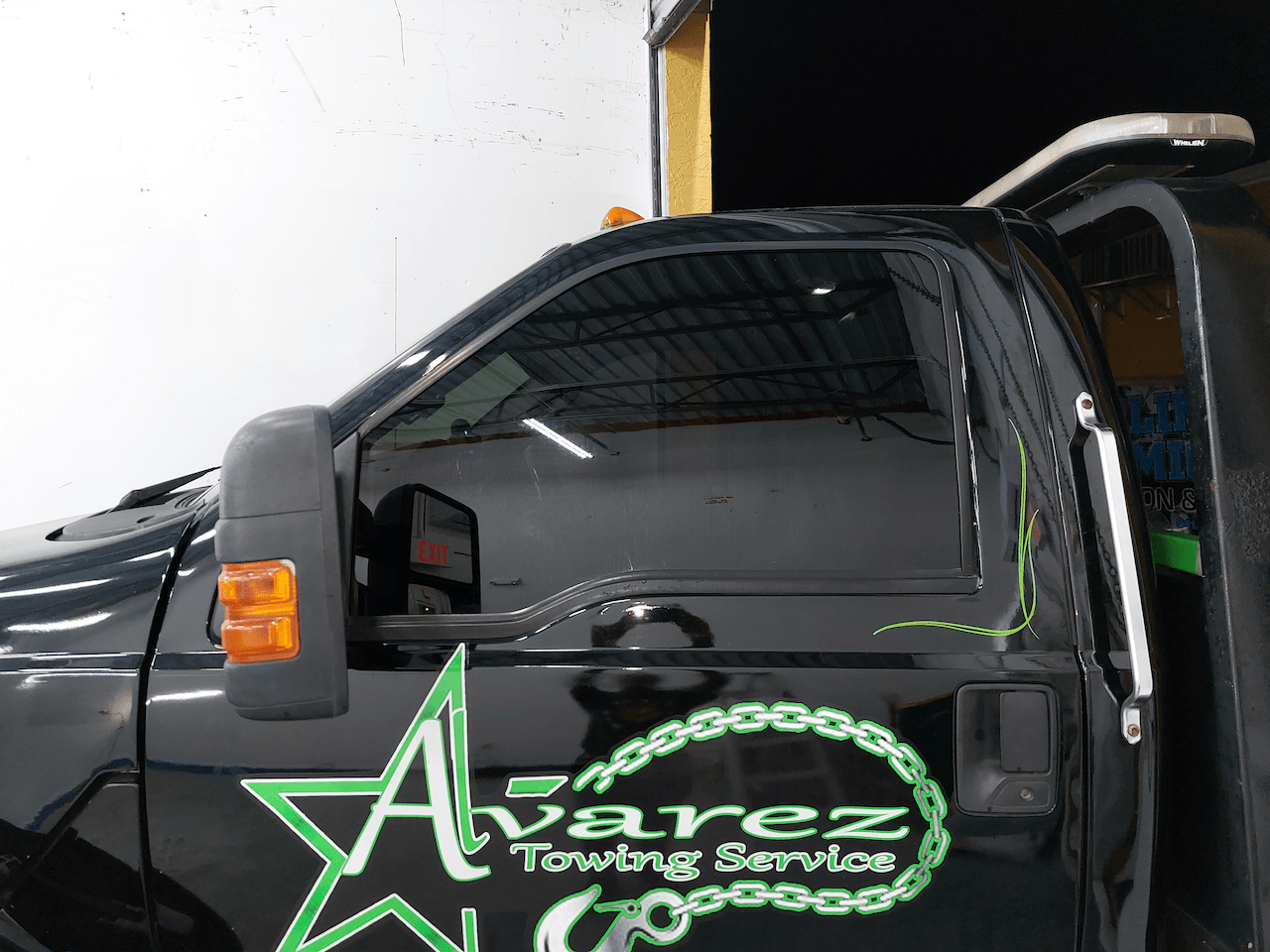 A black alvarez towing service truck with the door open