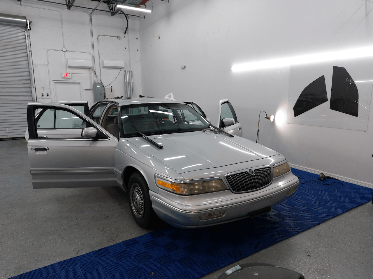 A silver car is parked in a garage with its doors open