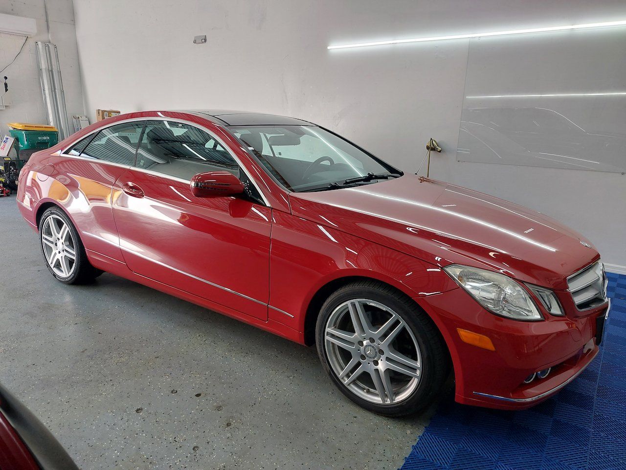 A red mercedes benz e class coupe is parked in a garage.