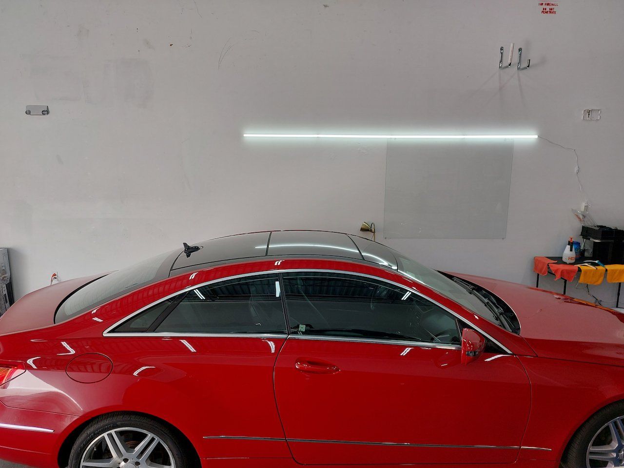 A red car is parked in a garage under a light