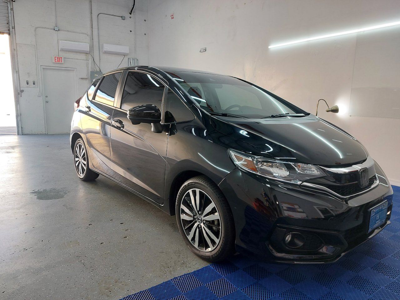 A black honda fit is parked in a garage.