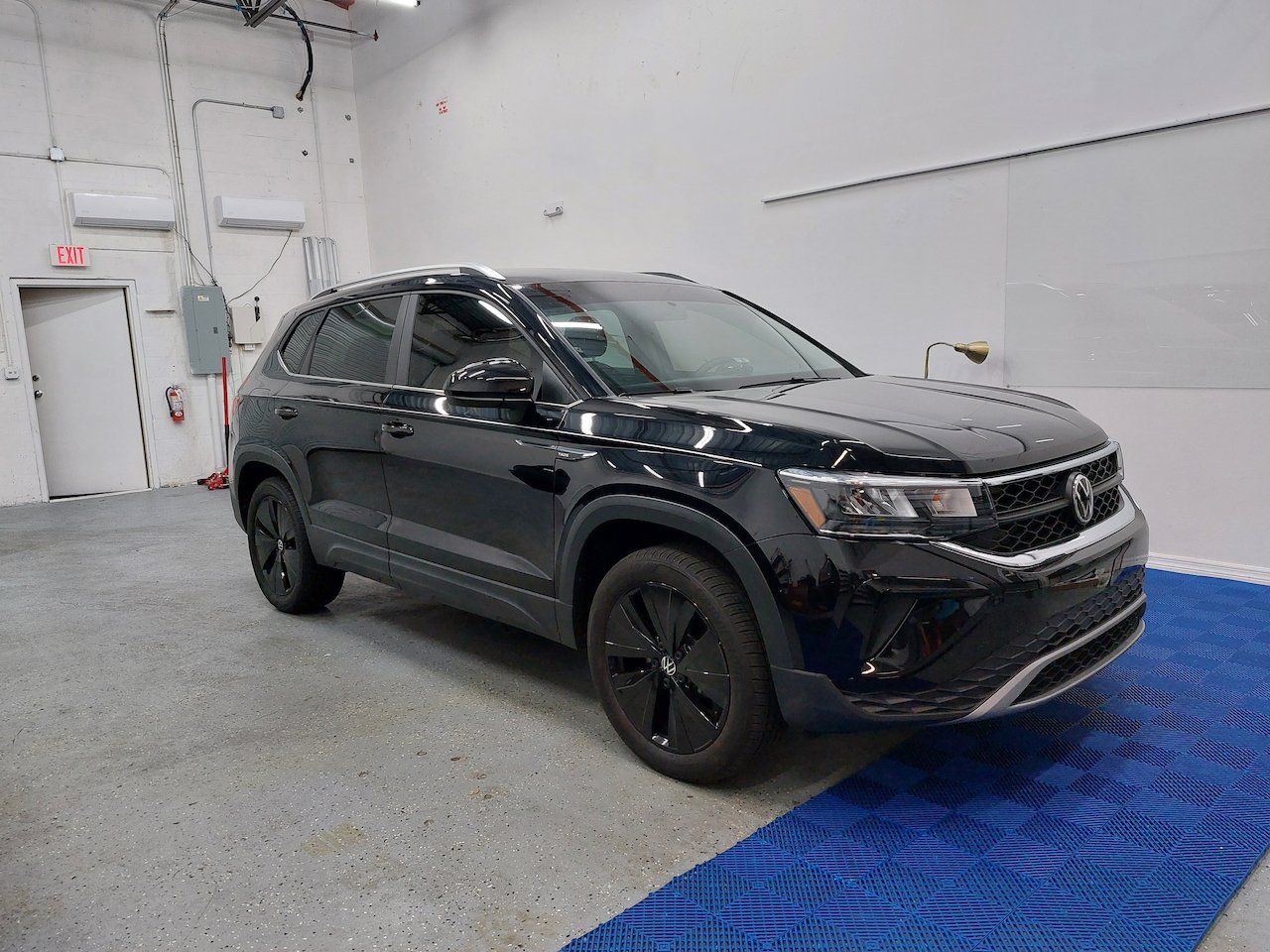 A black volkswagen taos is parked in a garage.