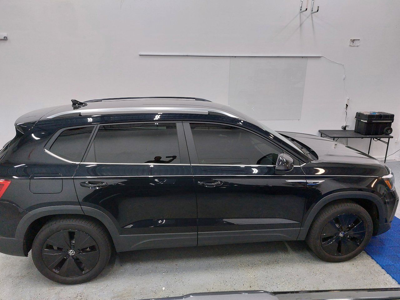 A black suv is parked in a garage next to a table.