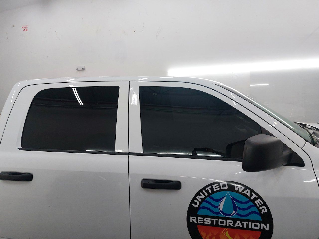 A white truck with a united water restoration logo on the side is parked in a garage.