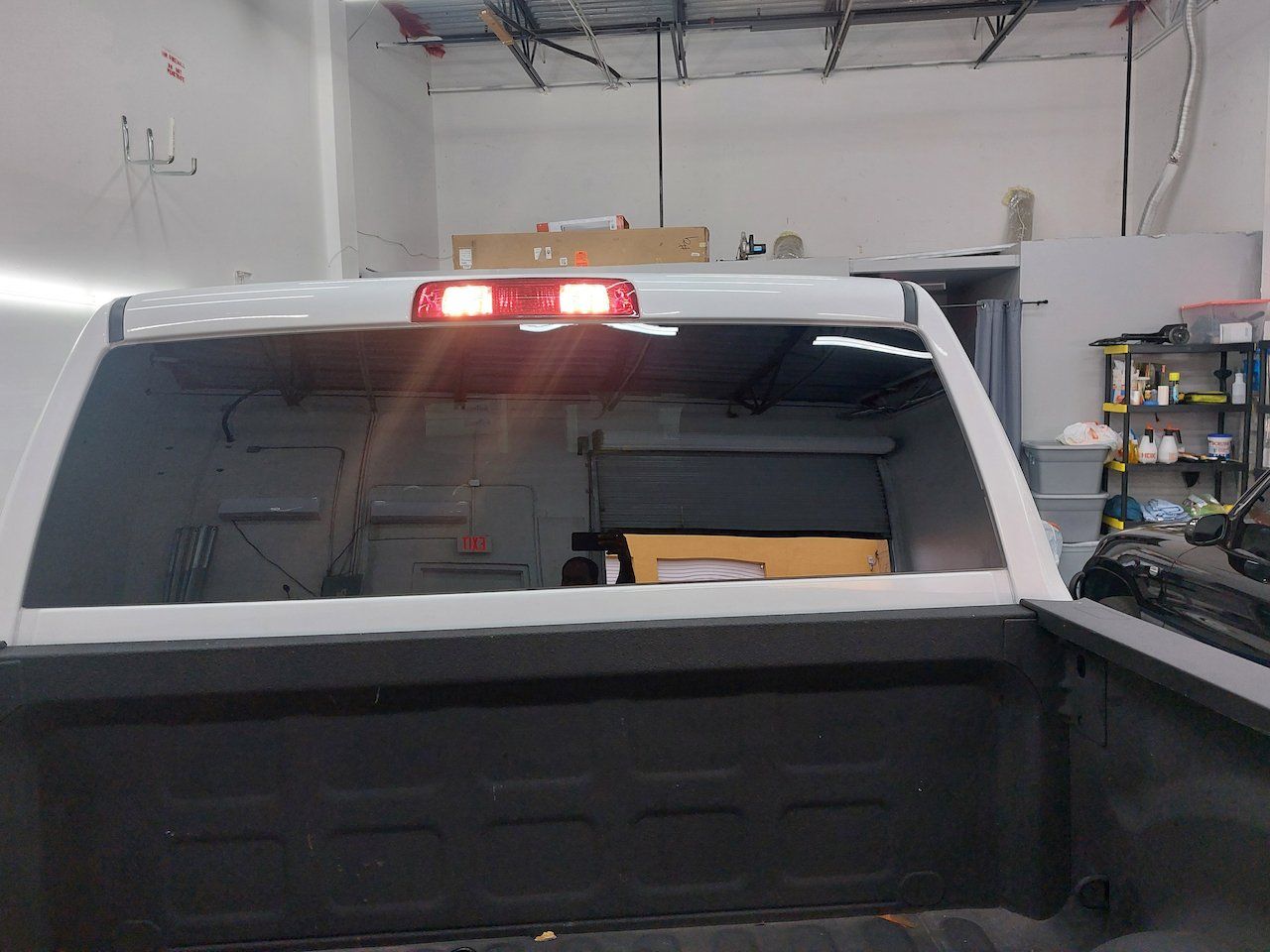 A white truck with a red tail light is parked in a garage