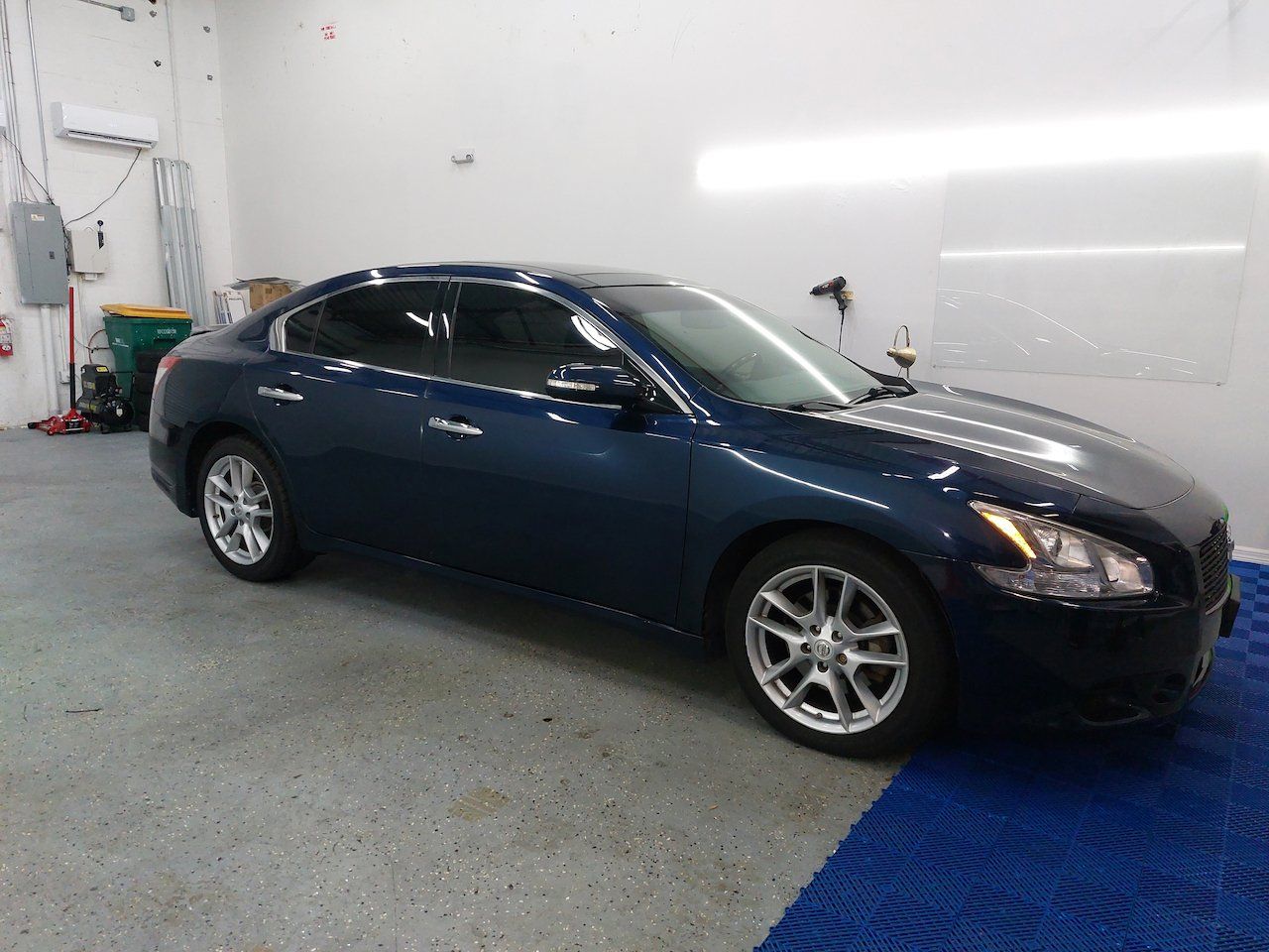 A blue car is parked in a garage.