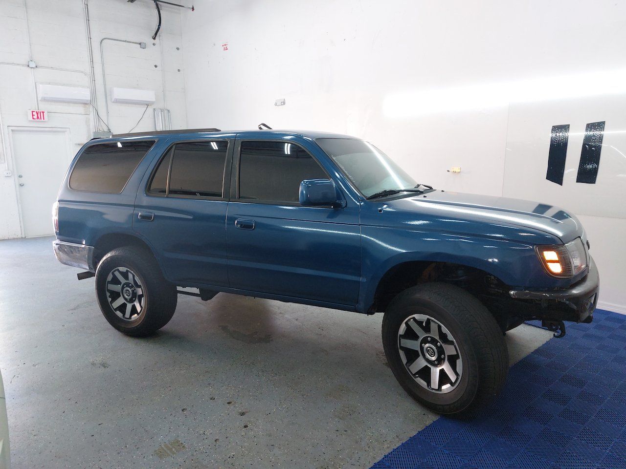 A blue toyota 4runner is parked in a garage.