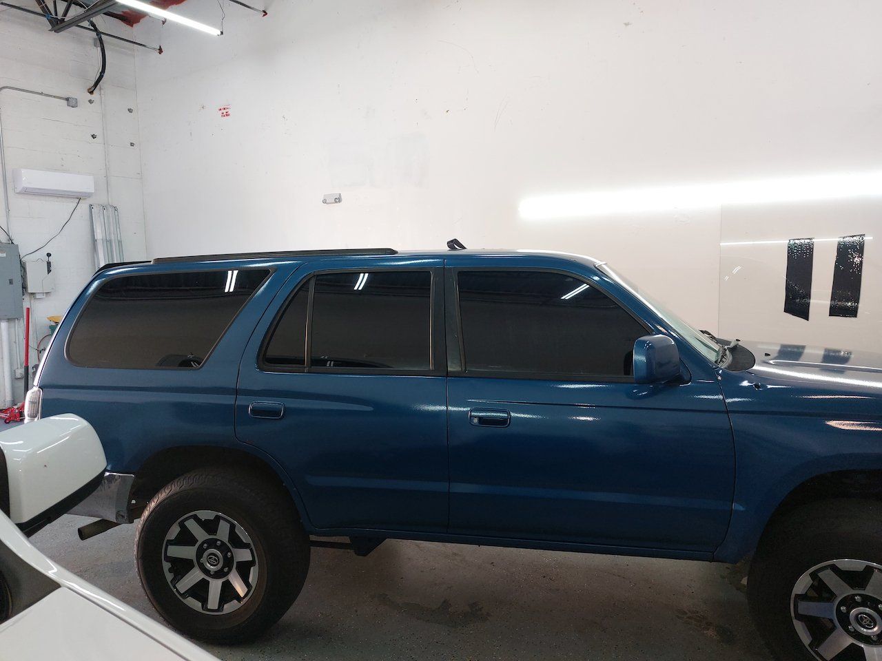 A blue suv is parked in a garage next to a white truck.
