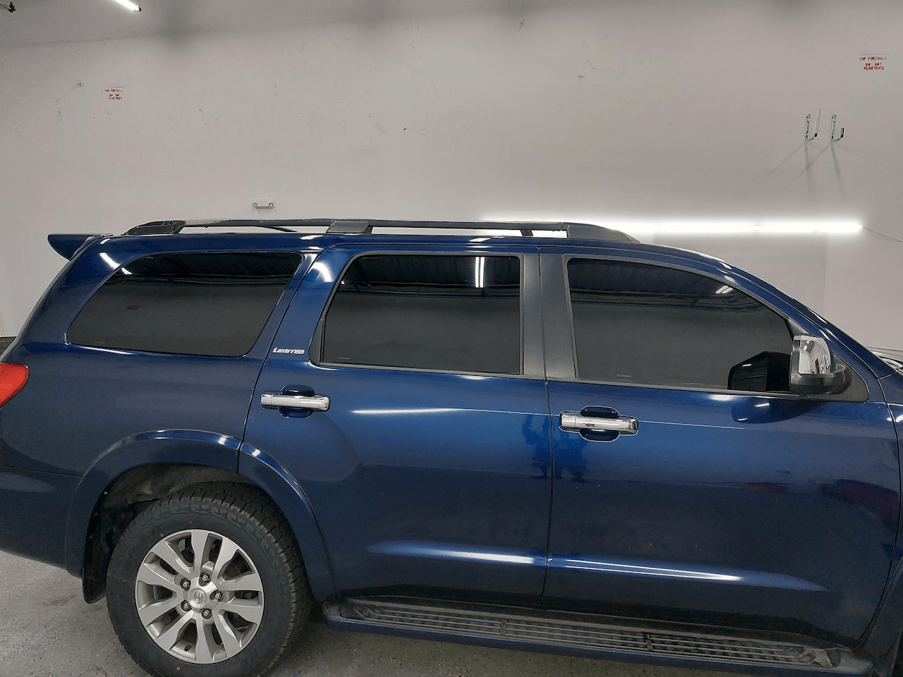 A blue toyota sequoia is parked in a garage.