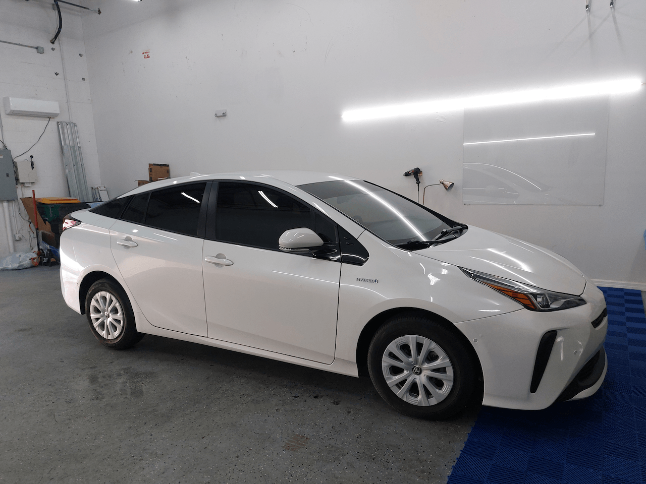 A white toyota prius is parked in a garage.
