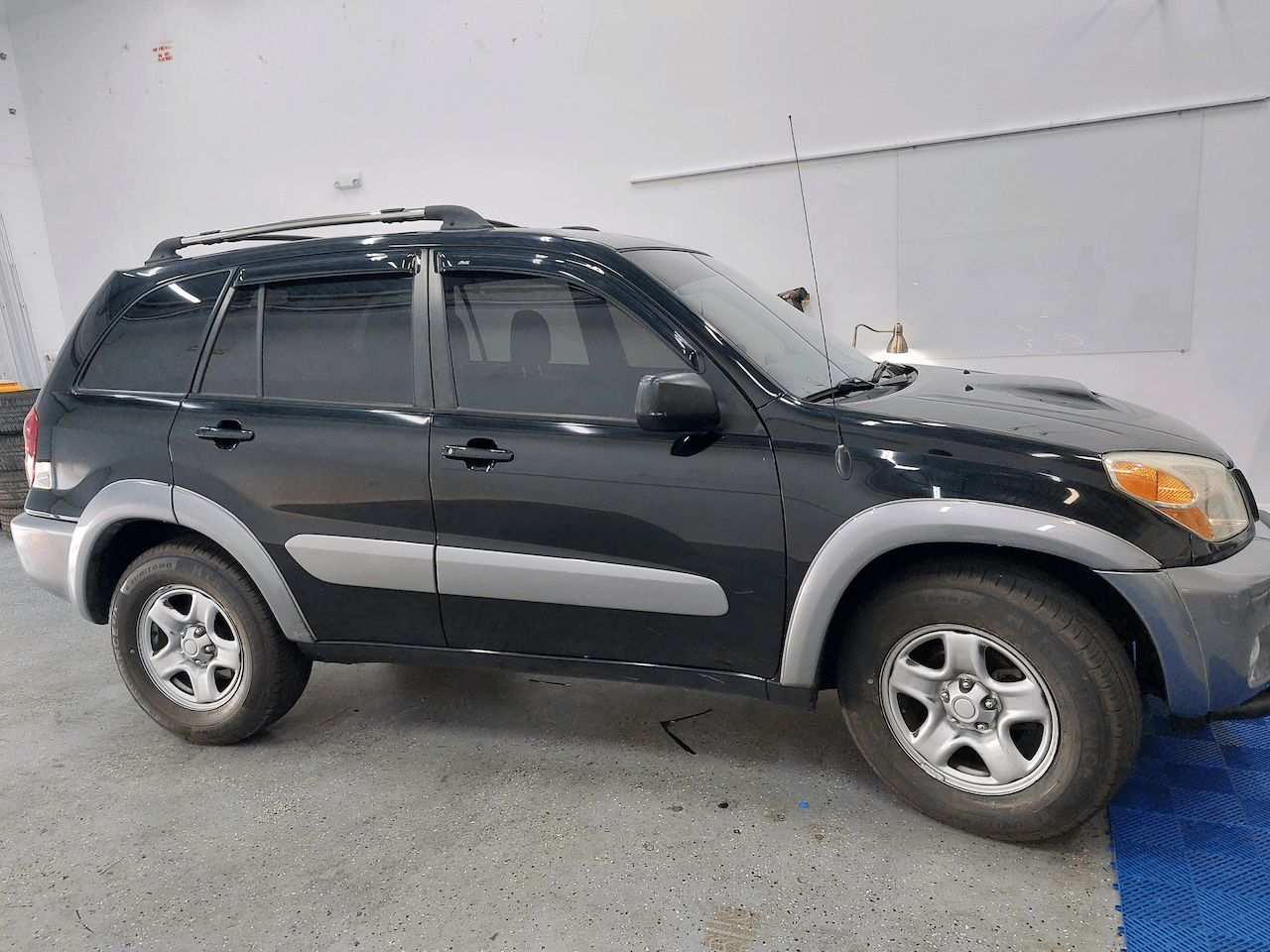 A black toyota rav4 is parked in a garage.