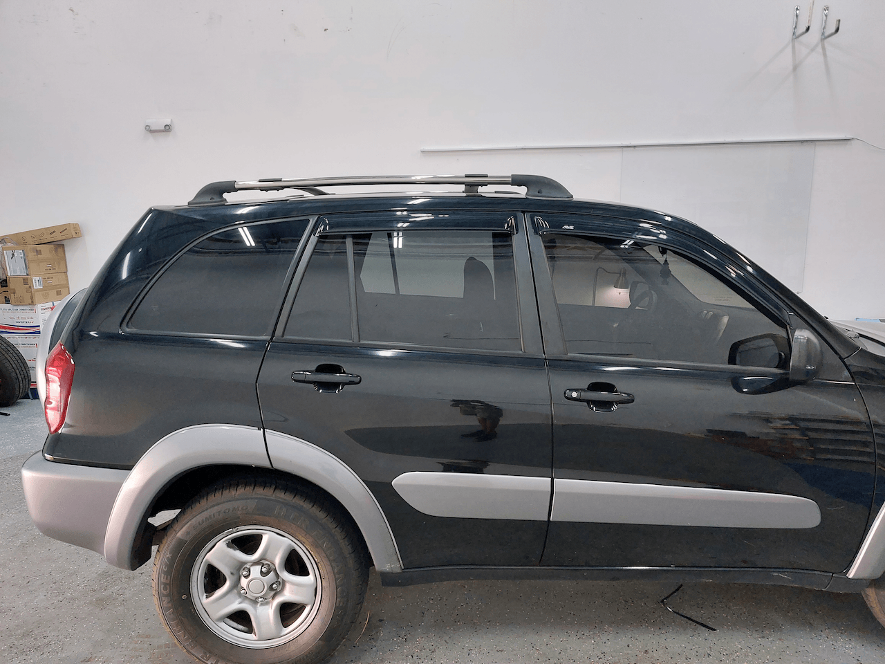 A black suv is parked in front of a white wall