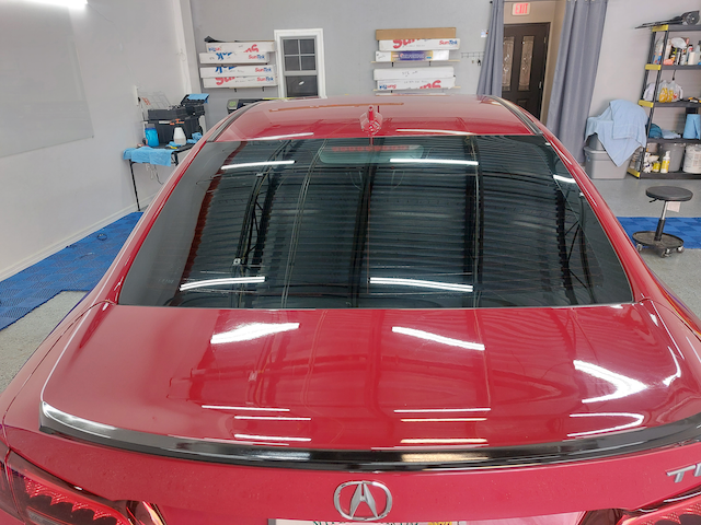 A red acura car is parked in a garage