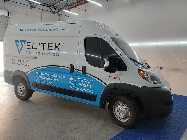 A white and blue van is parked in a garage.