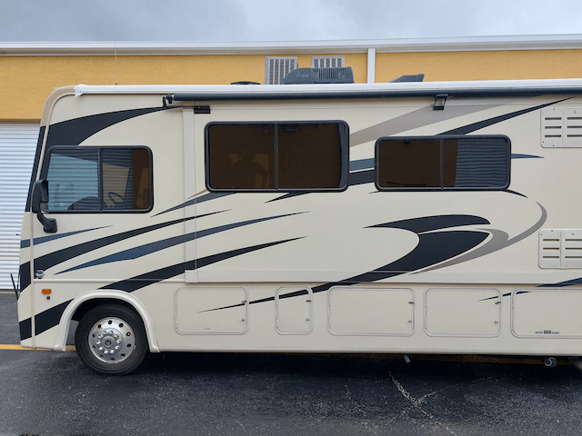 A white rv is parked in front of a yellow building