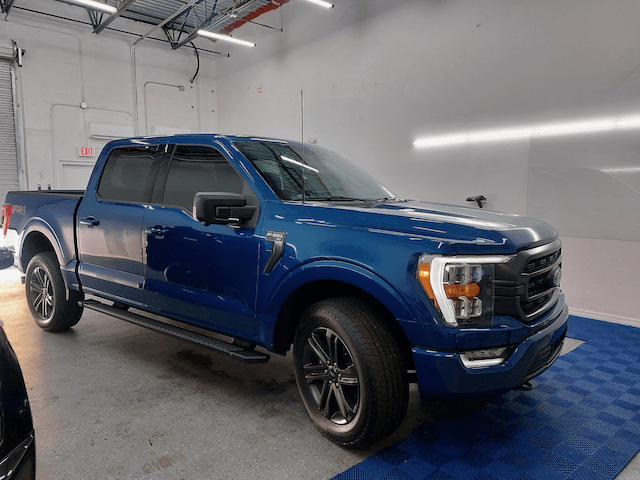 A blue pickup truck is parked in a garage.