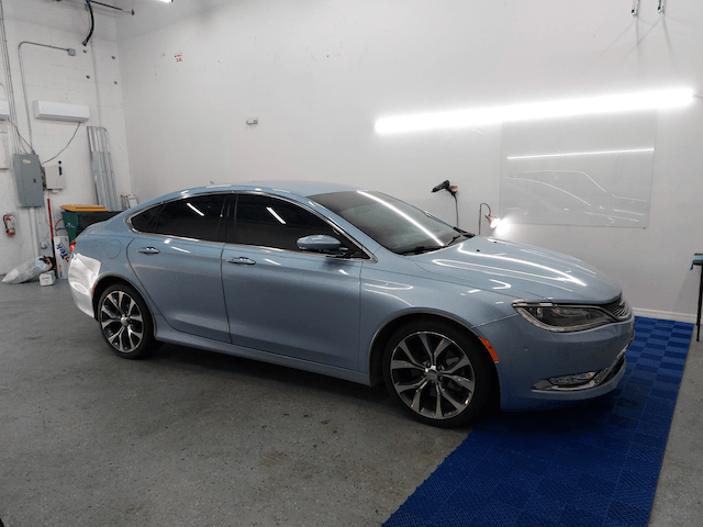 A light blue car is parked in a garage.