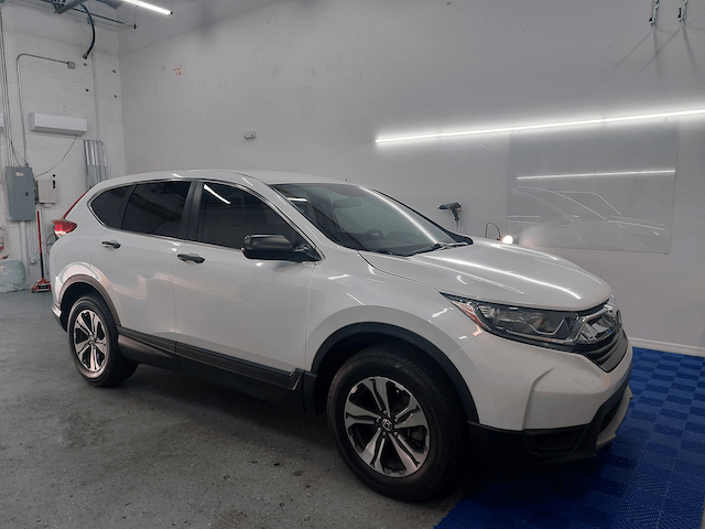 A white honda cr v is parked in a garage.