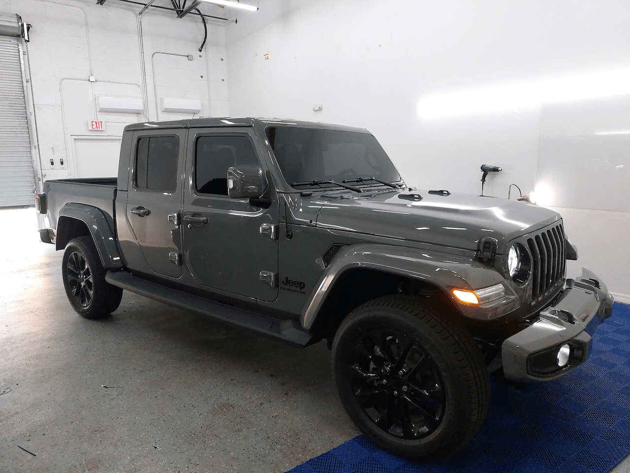 A gray jeep gladiator is parked in a garage.