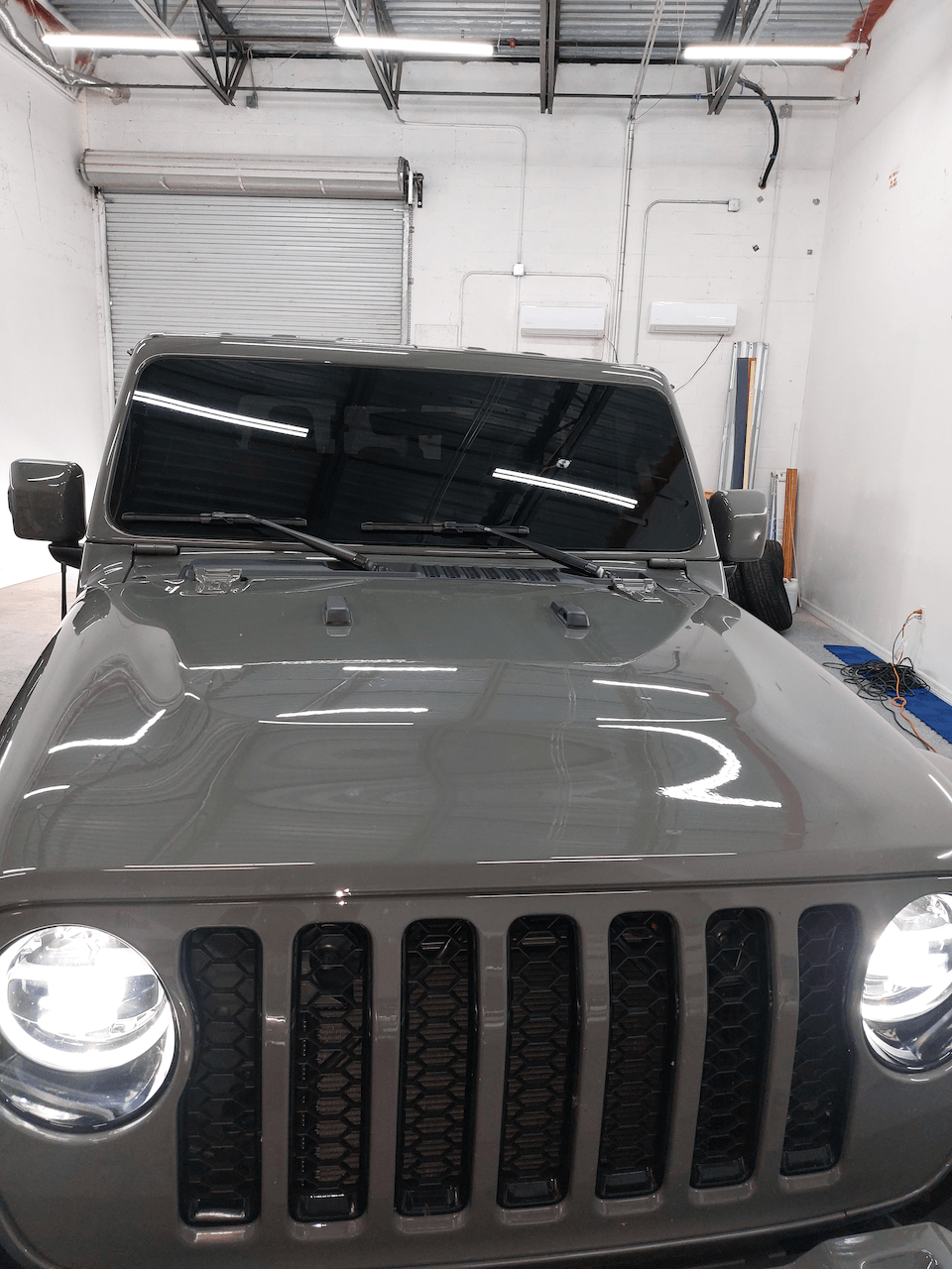 A jeep is parked in a garage with its hood up.