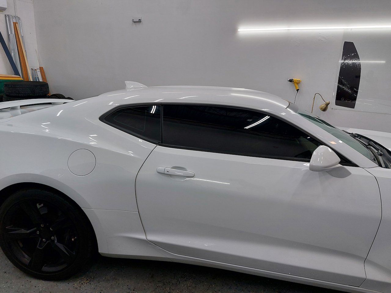 A white car with black wheels is parked in a garage.