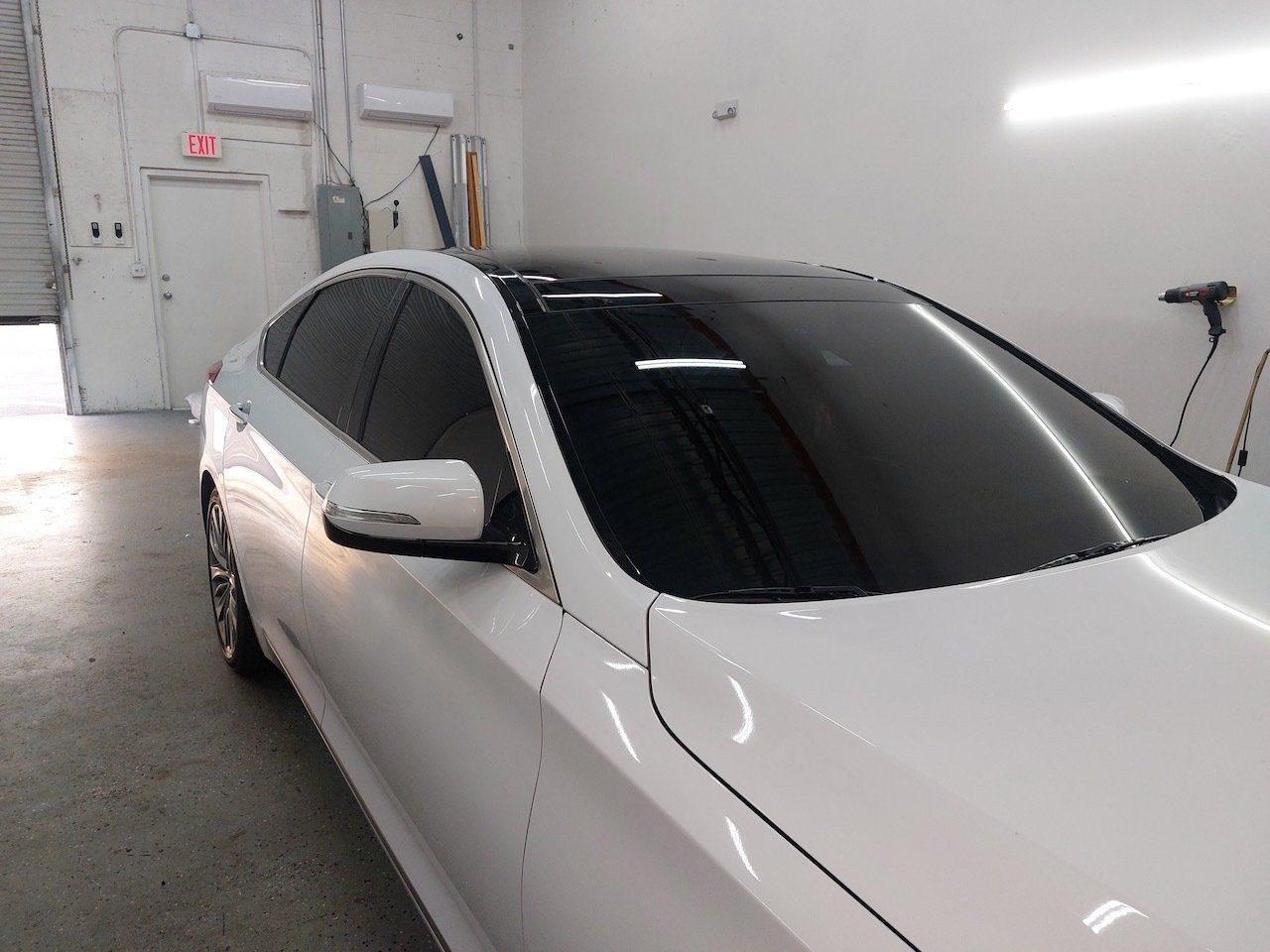 A white car with a black roof is parked in a garage.
