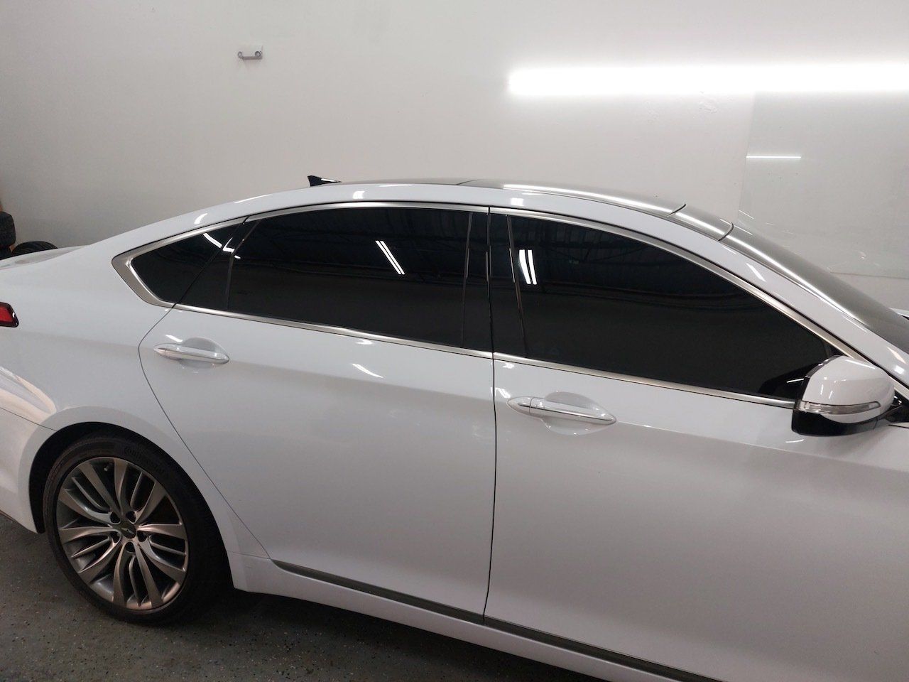 A white car with tinted windows is parked in a garage.