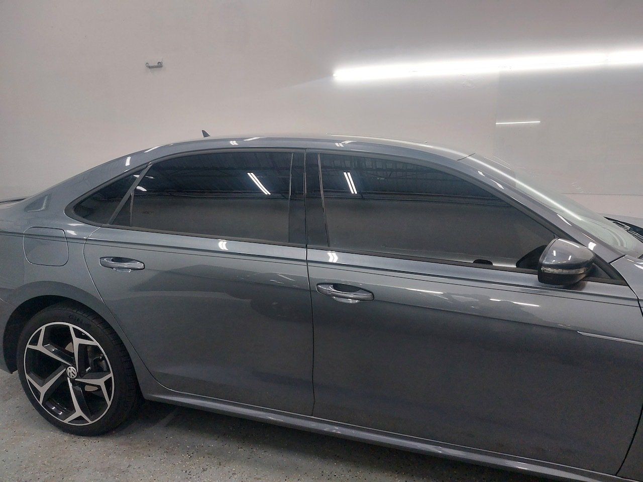 A gray car with tinted windows is parked in a garage.
