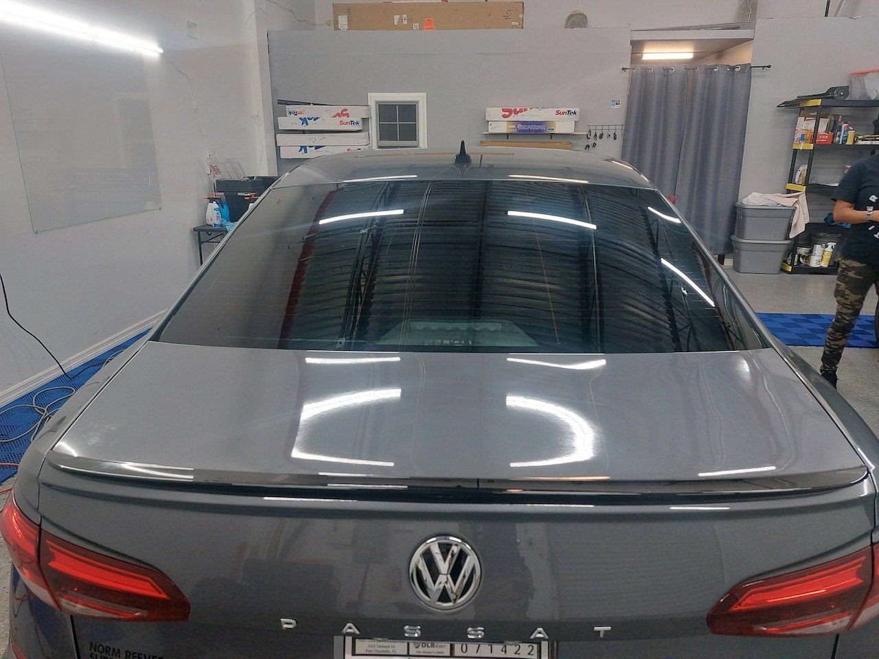 A man is standing next to a gray volkswagen in a garage.