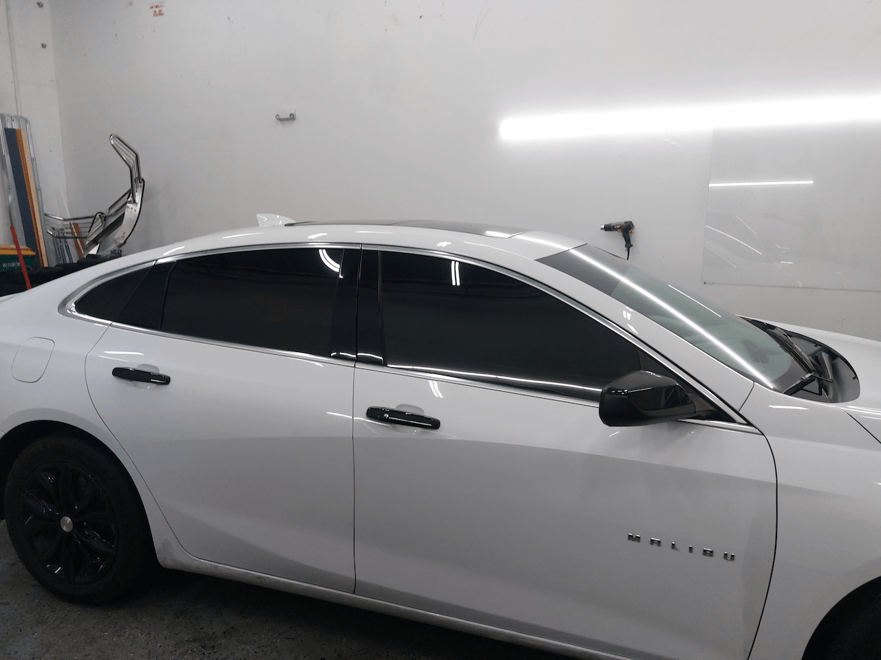A white car with black windows is parked in a garage.