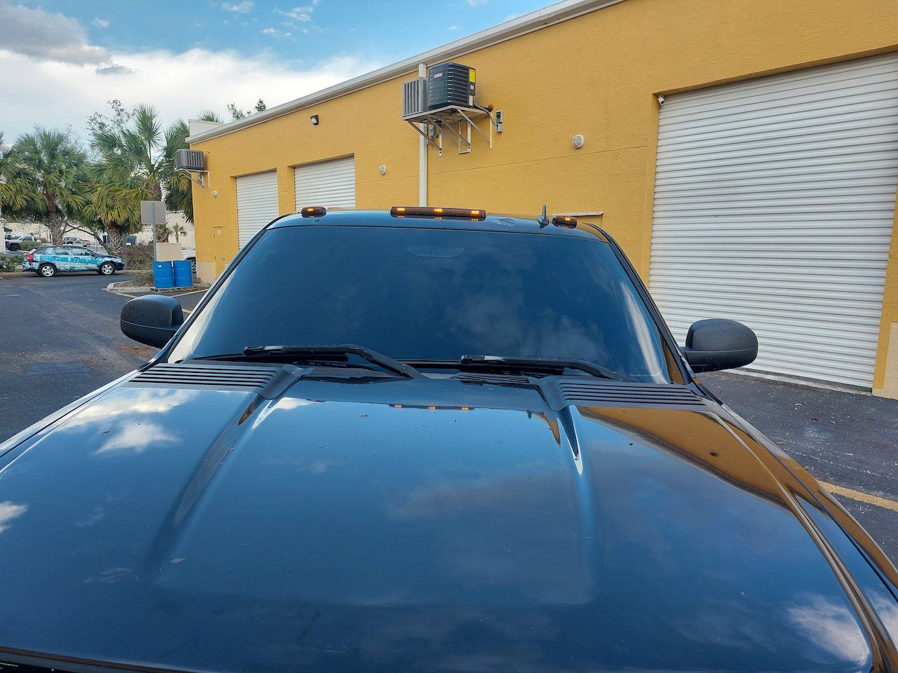 A black truck is parked in front of a yellow building.