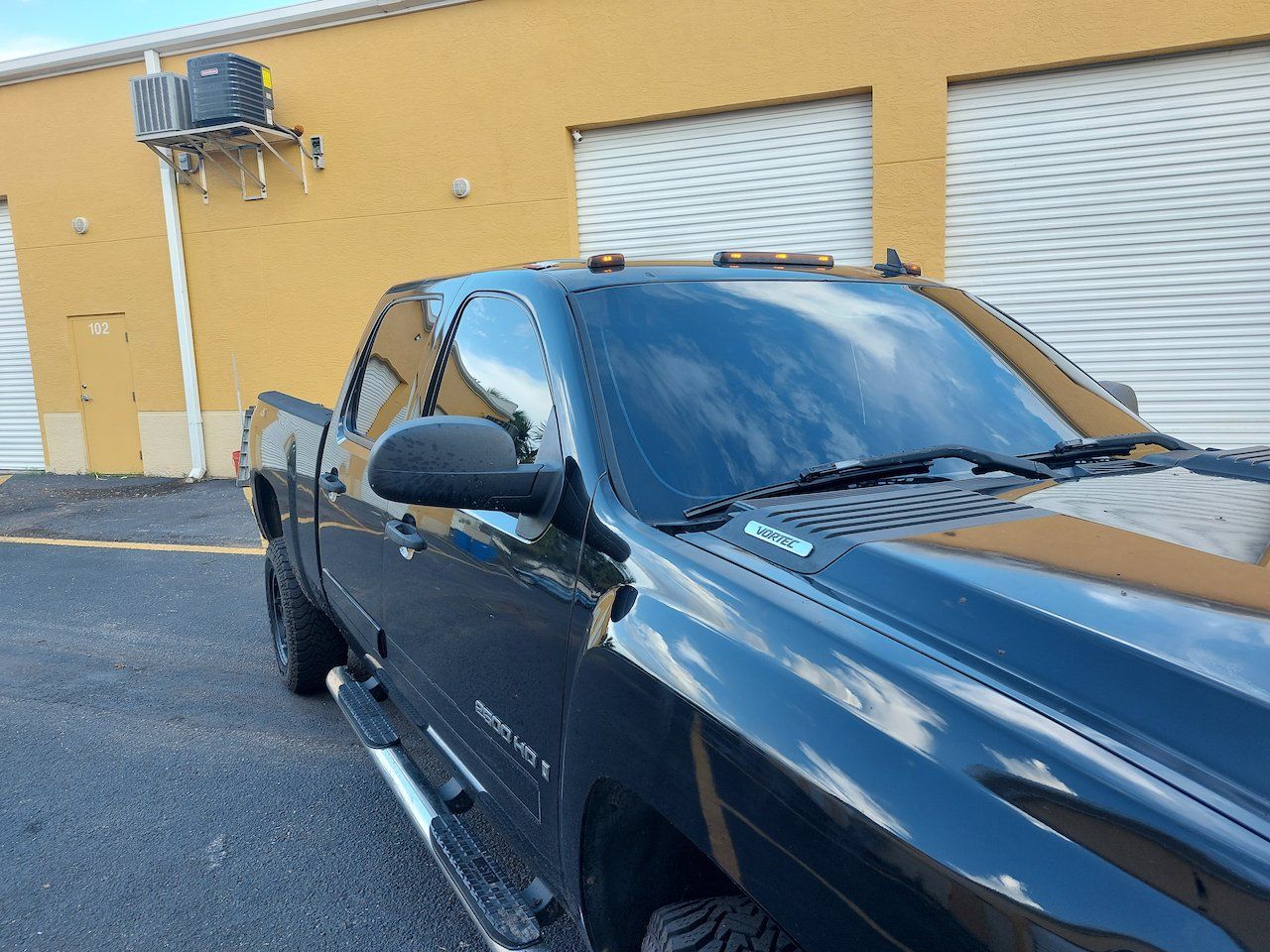 A black truck is parked in front of a yellow building