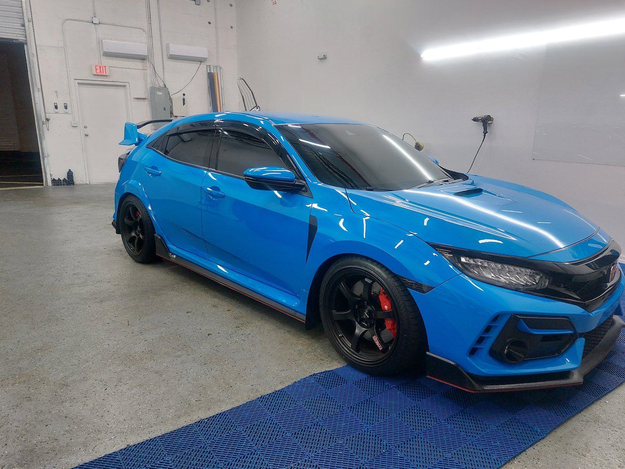 A blue honda civic type r is parked in a garage.