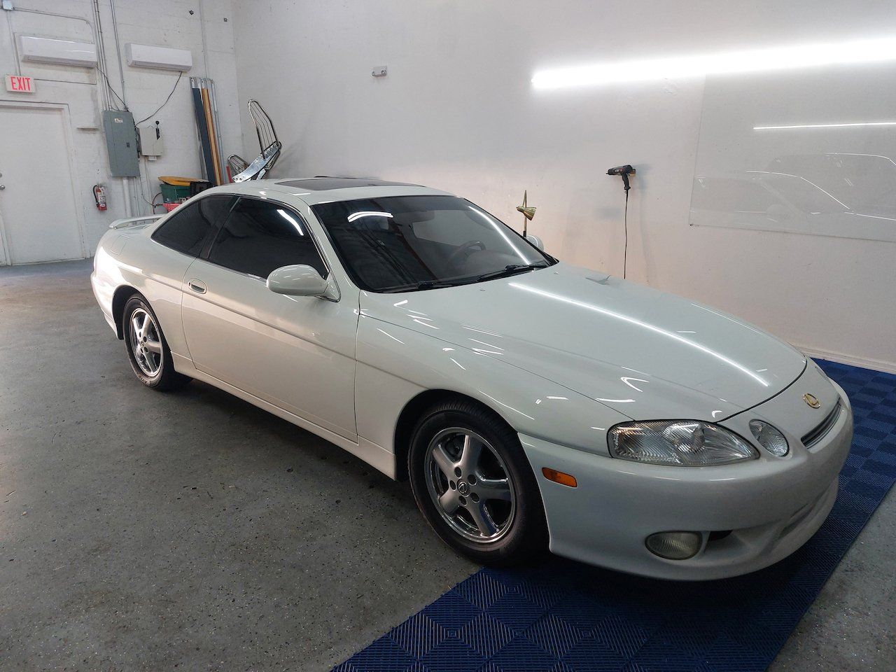 A white sports car is parked in a garage.