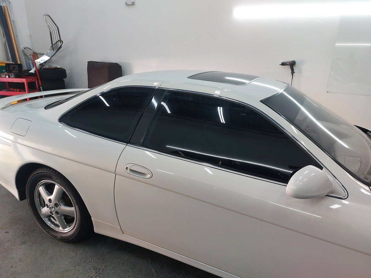 A white car with black windows is parked in a garage.