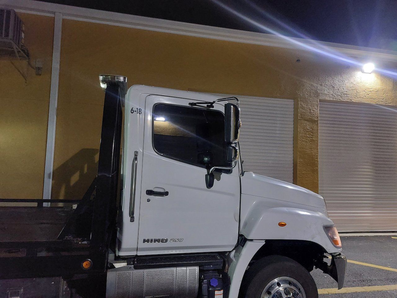 A white tow truck is parked in front of a building at night