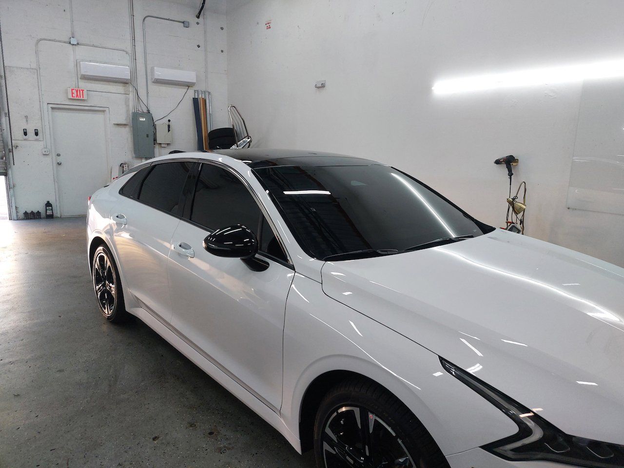 A white car with black windows is parked in a garage.