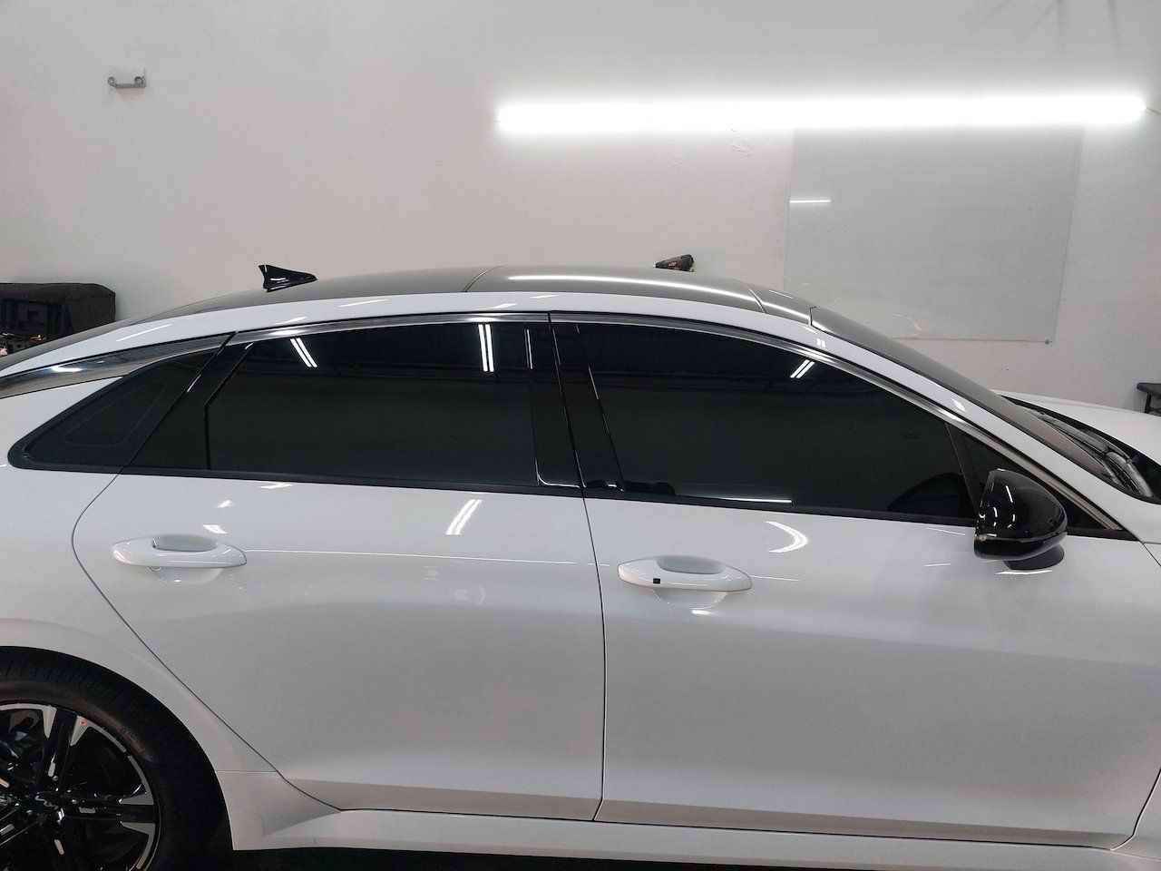 A white car with black windows is parked in a garage.