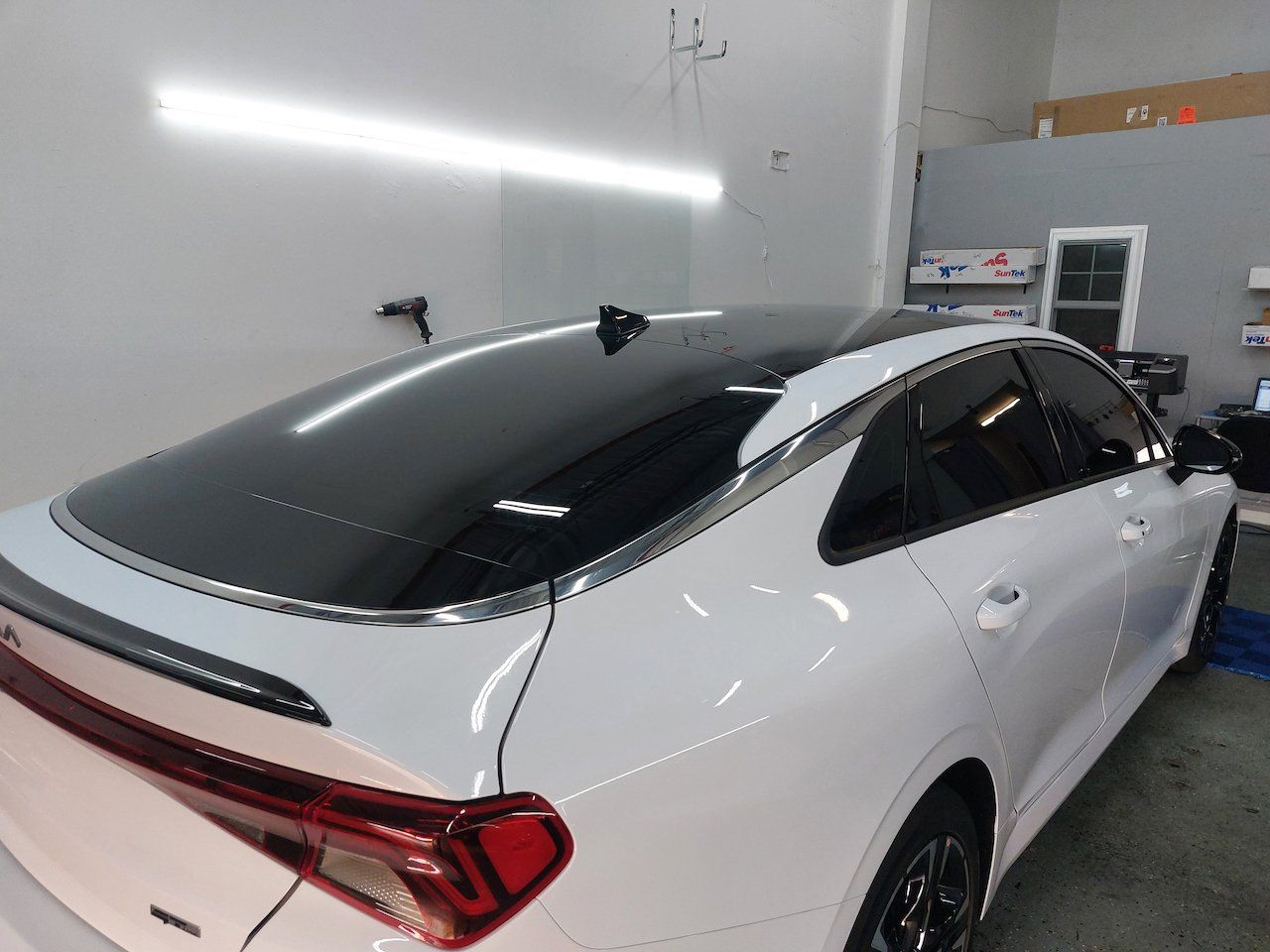 A white car with a black roof is parked in a garage.