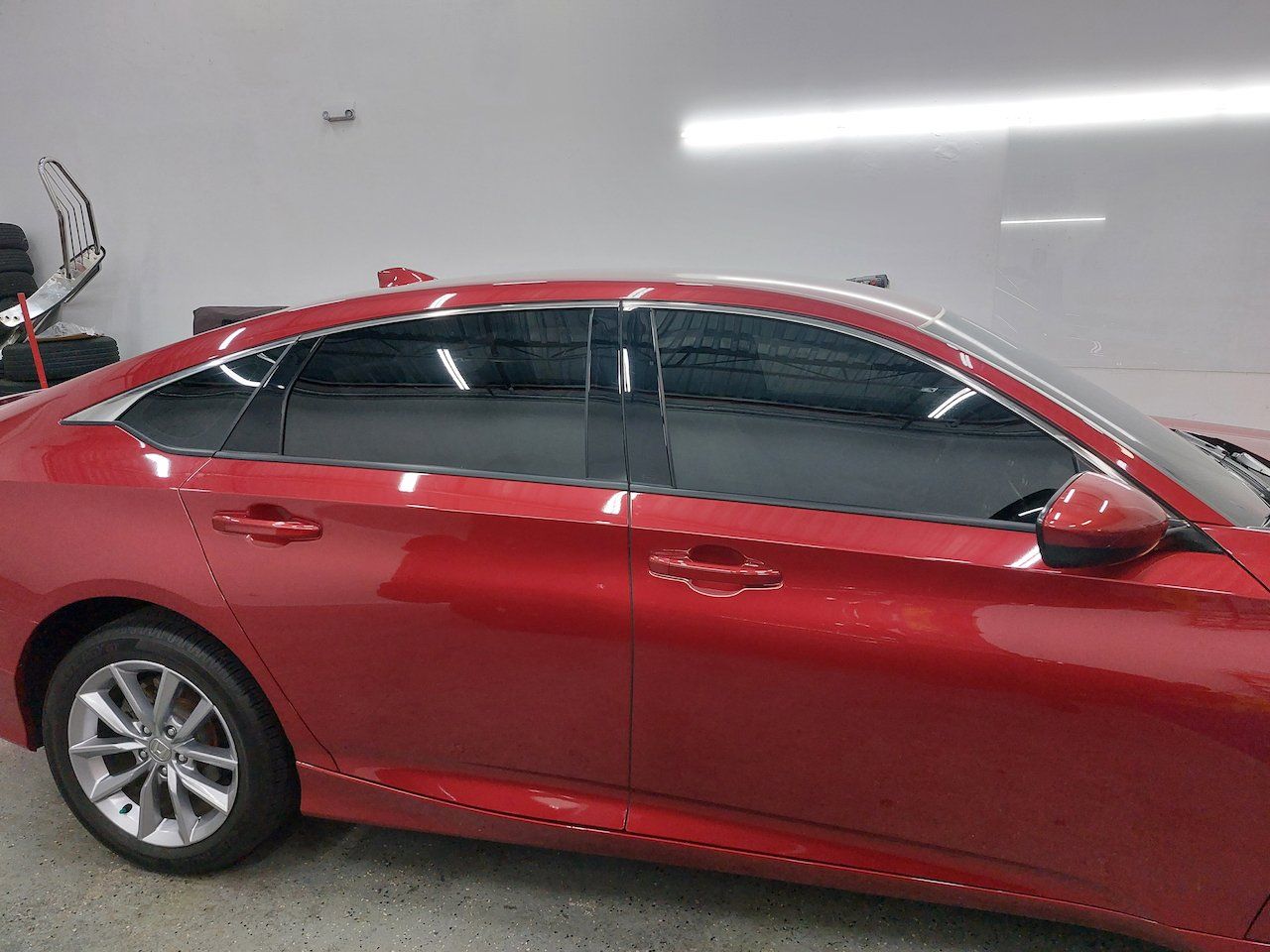 A red car with tinted windows is parked in a garage.