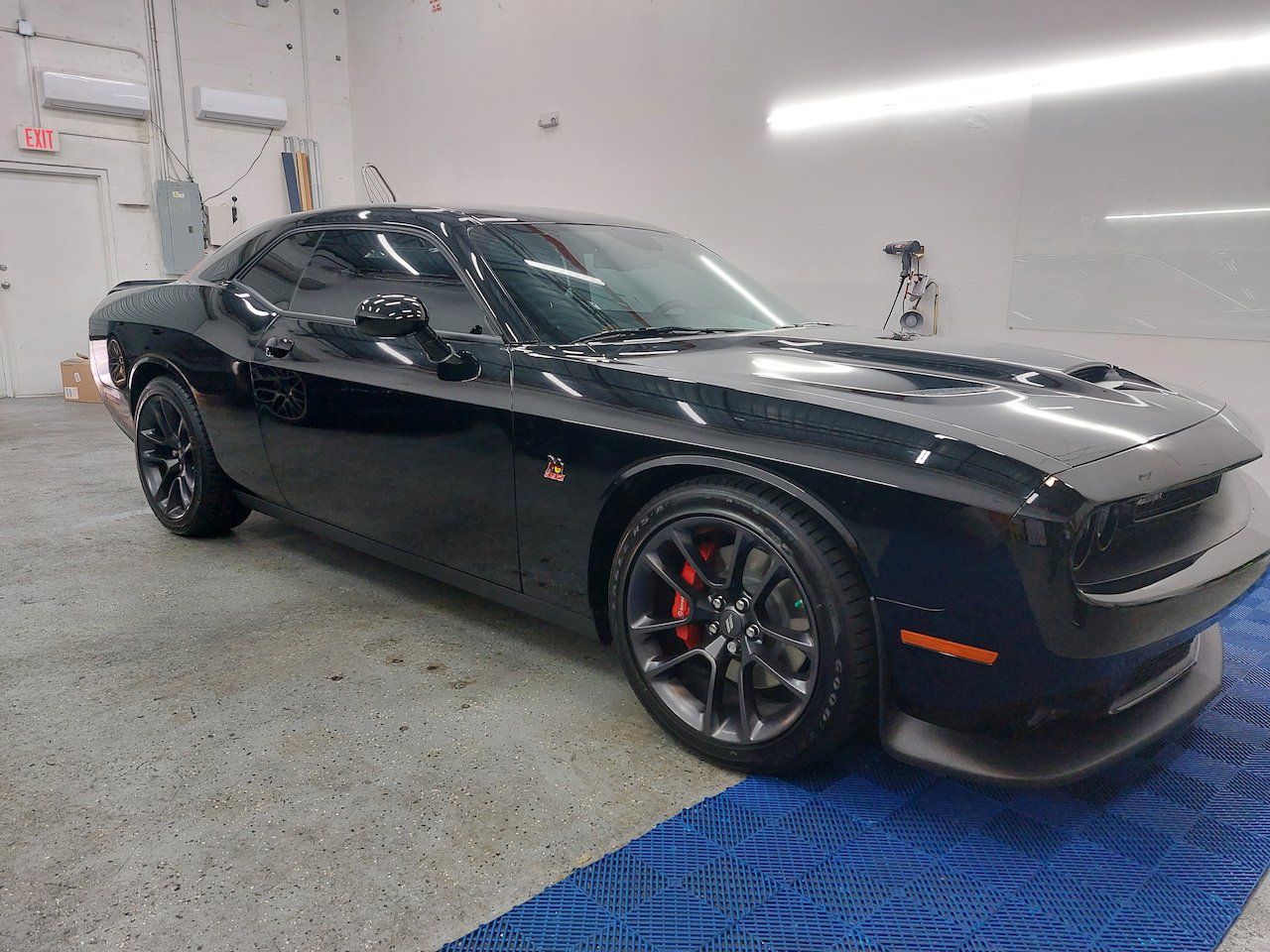A black dodge challenger is parked in a garage.