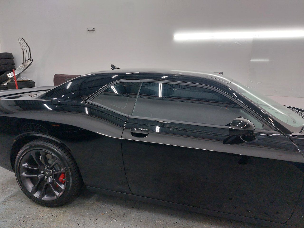 A black dodge challenger is parked in a garage.