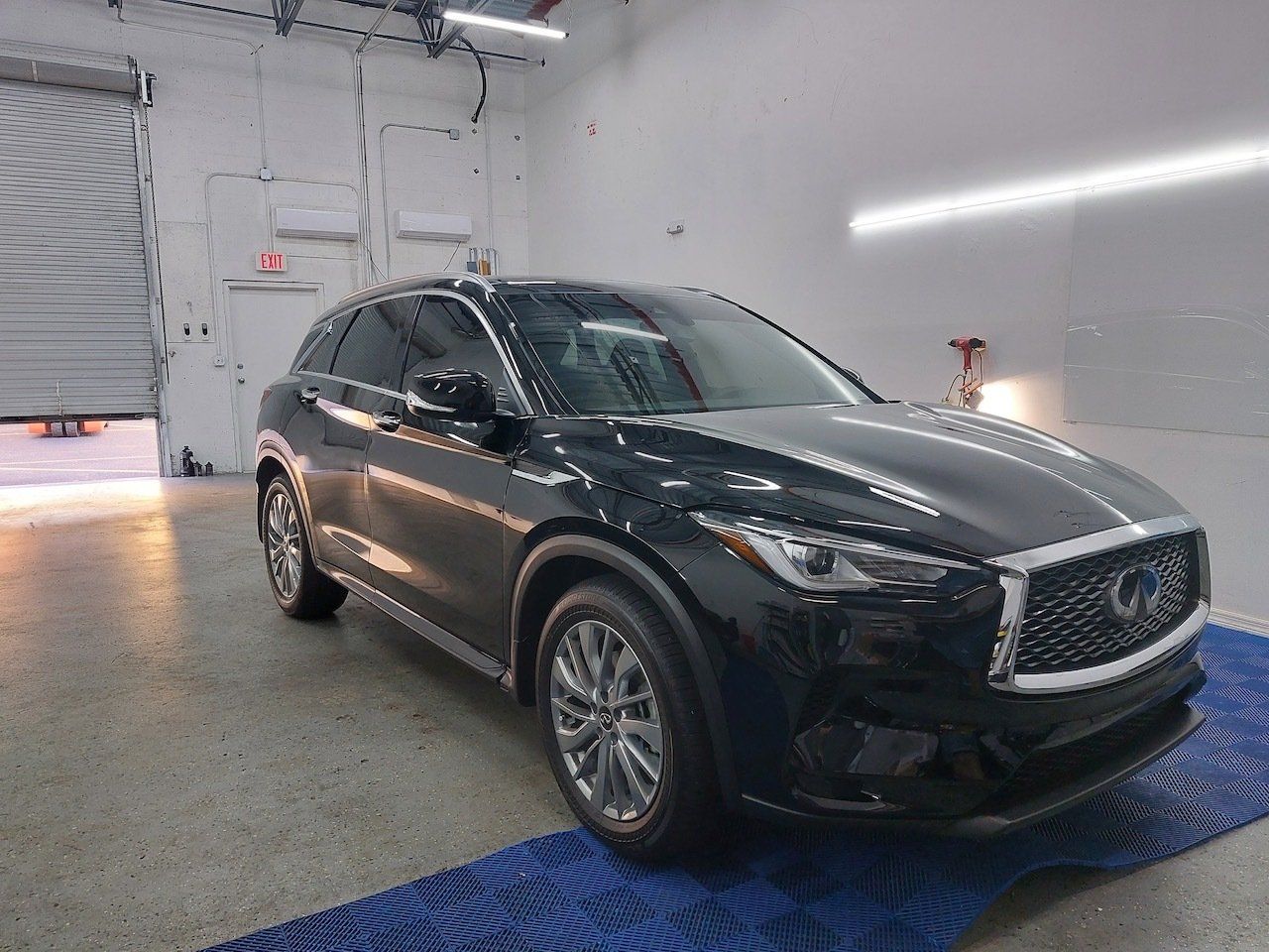 A black infiniti q50 is parked in a garage.