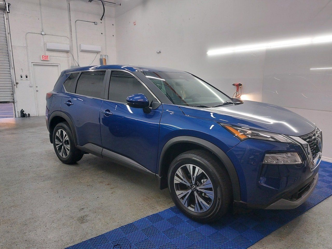 A blue nissan rogue is parked in a garage.