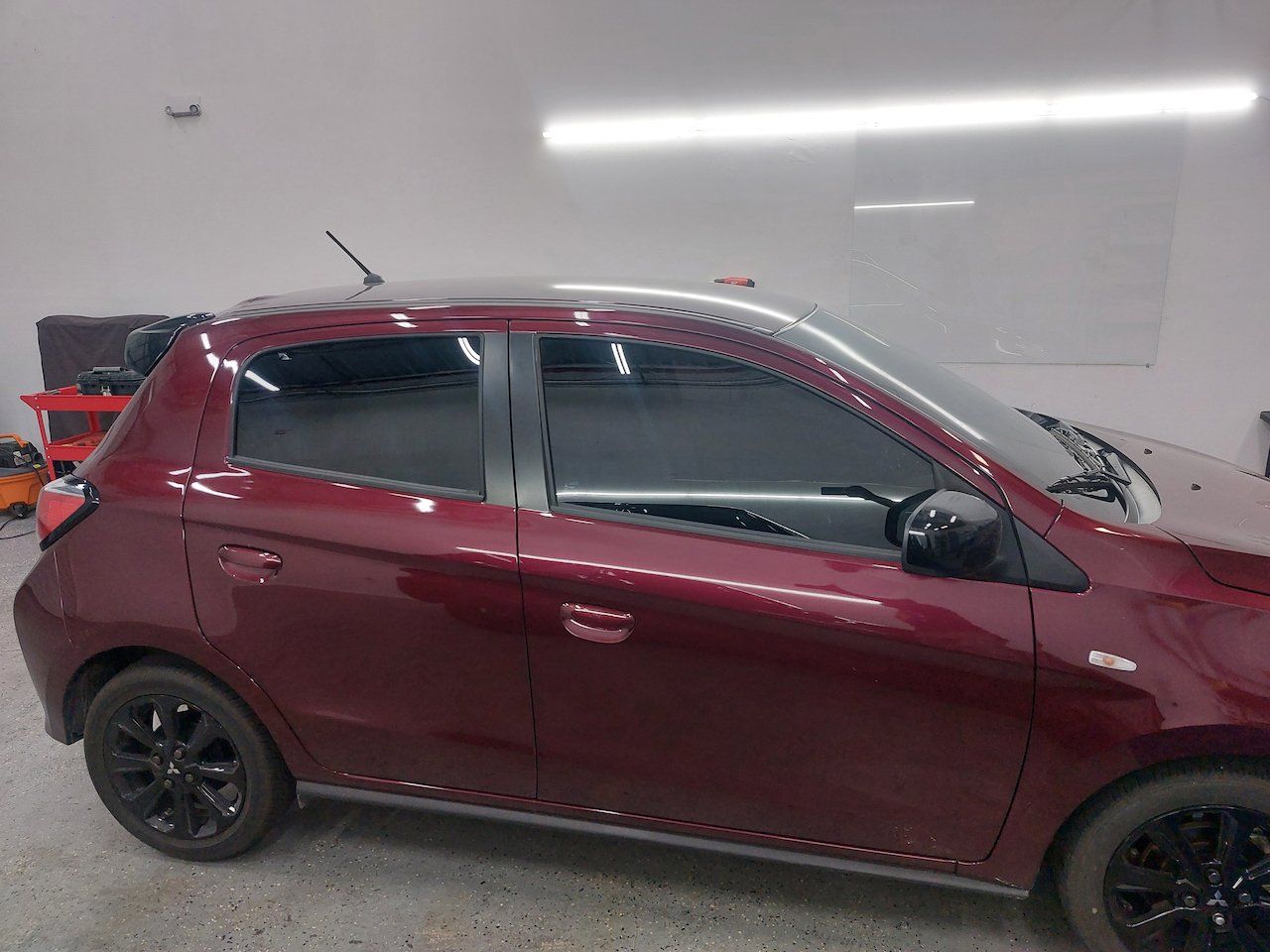 A red car with black wheels is parked in a garage.