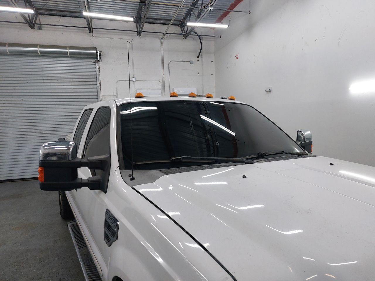 A white truck is parked in a garage.