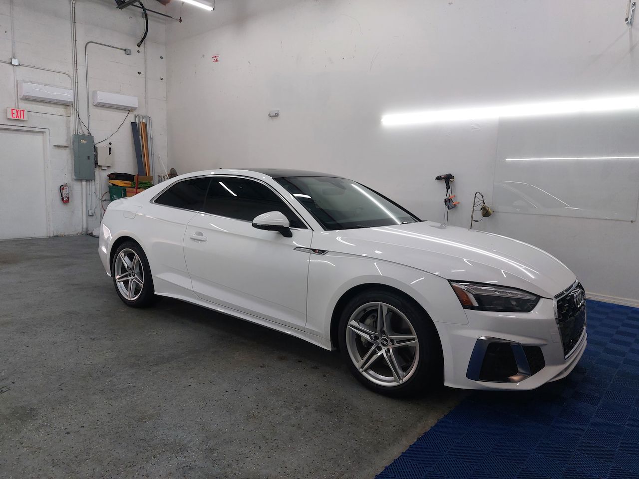 A white audi a5 coupe is parked in a garage.